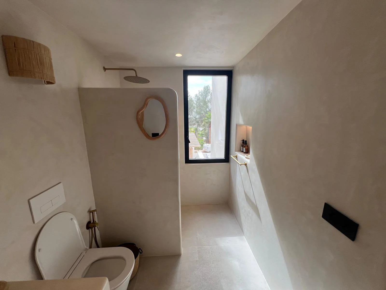 Bathroom renovation Ibiza — microcement walk-in shower with window view