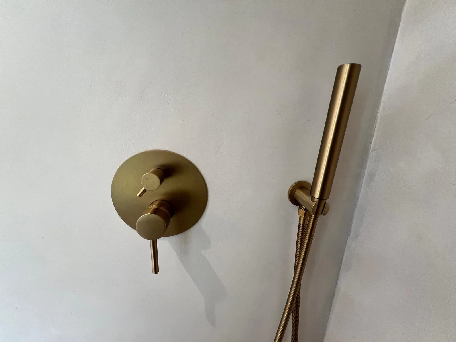 Grifo empotrado en oro mate sobre microcemento — detalle reforma baño Ibiza