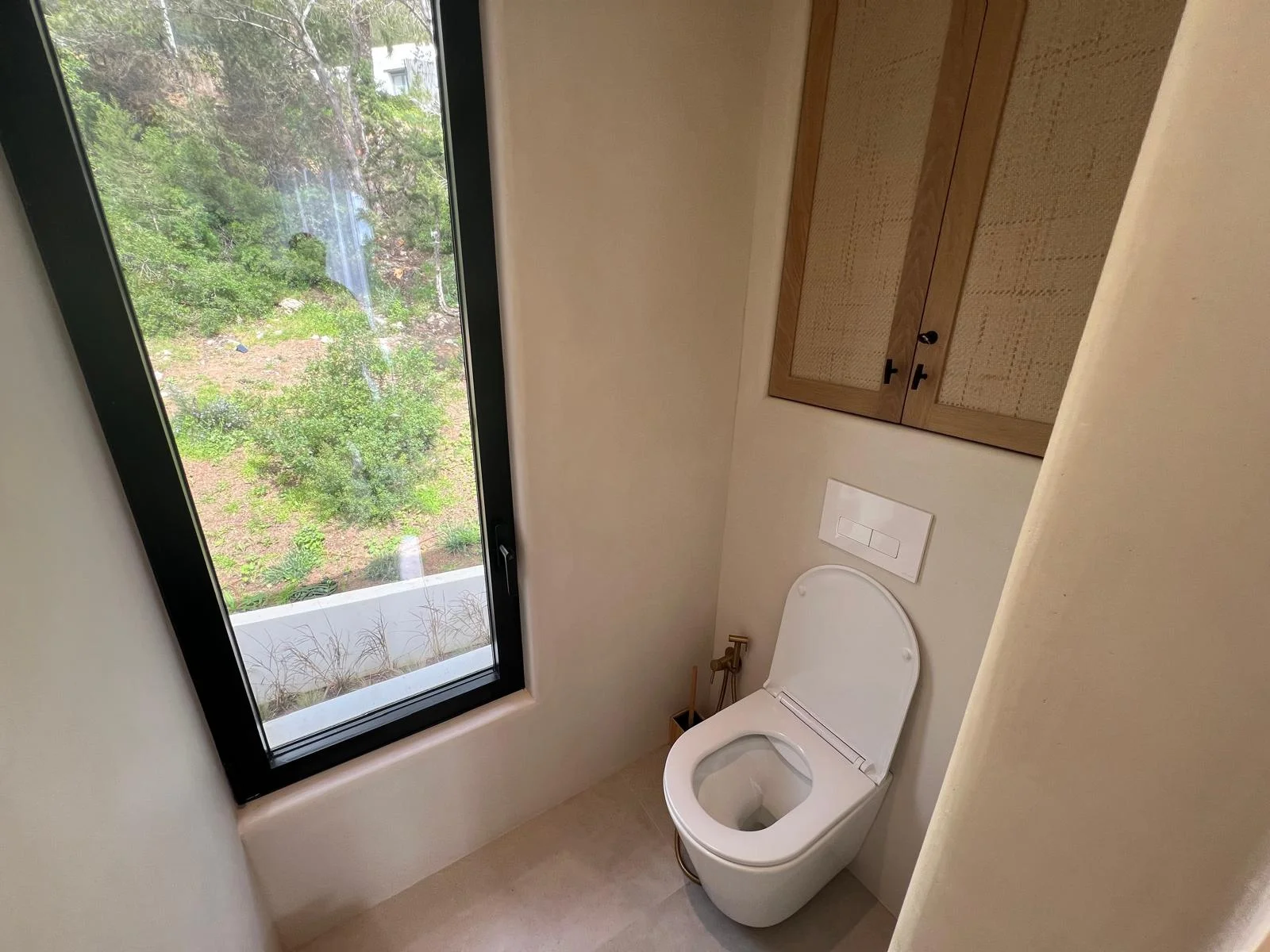 Baño con inodoro suspendido, ventana y armario de ratán — villa Ibiza