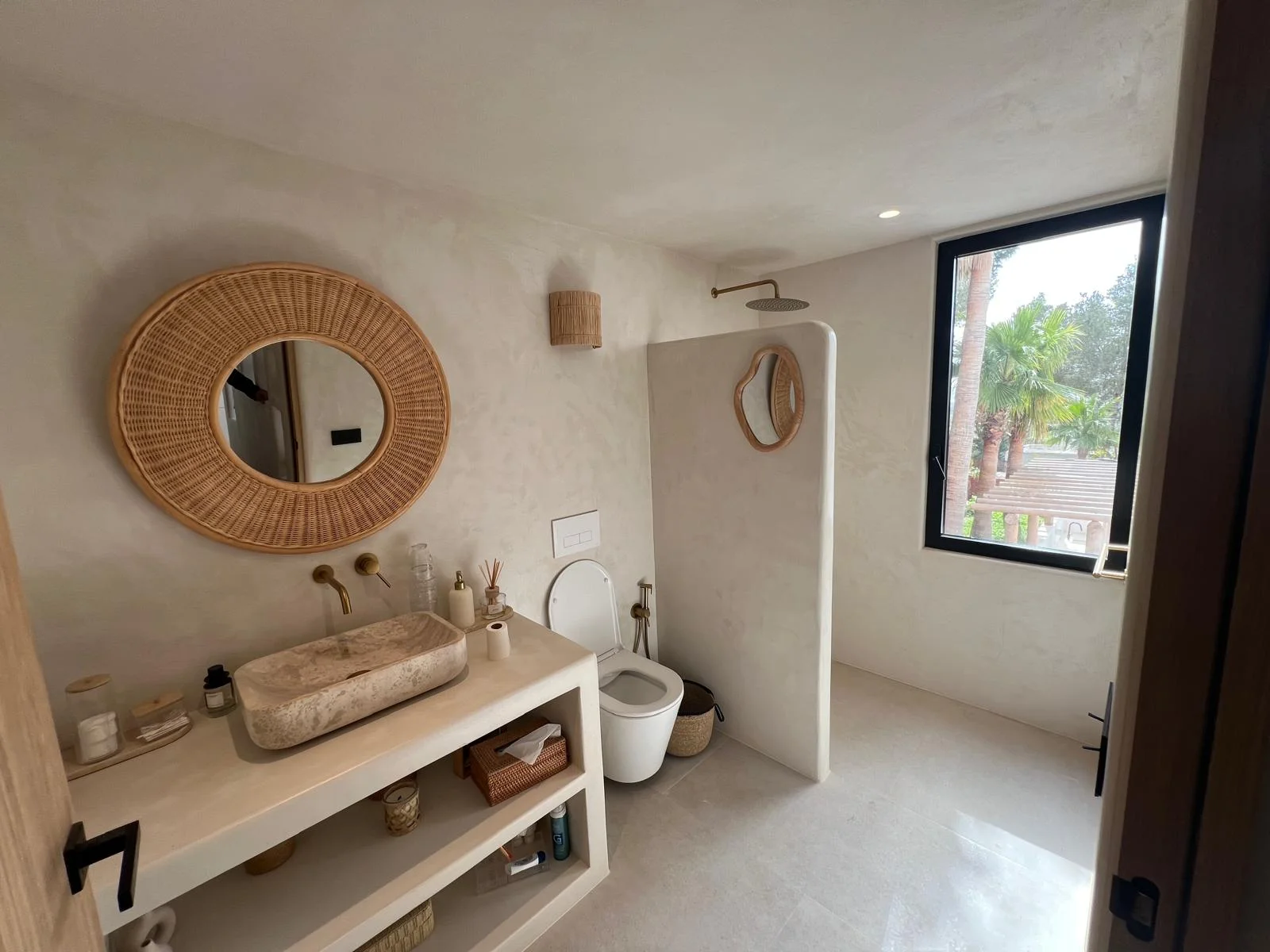 Lavabo travertino, espejo de ratán y ducha lluvia — villa Ibiza