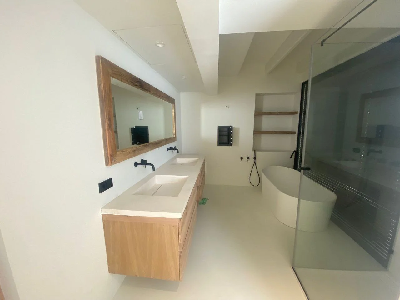 Baño con microcemento, bañera exenta y detalle en madera — villa Ibiza